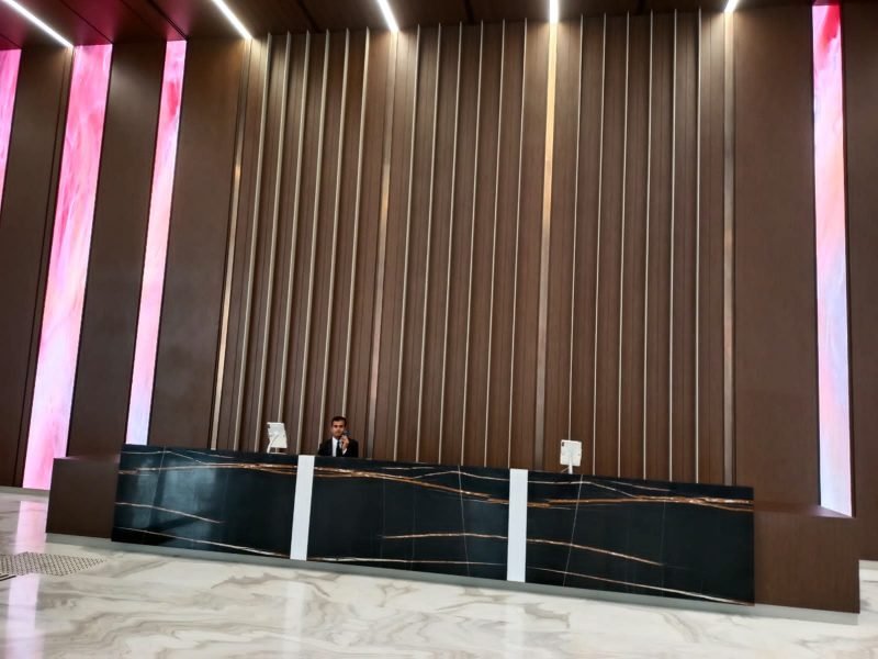 Reception counter with brass inlay strips and fluted metal wall panels, installed