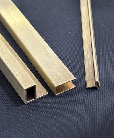Brass architectural profile section on a dark cloth background