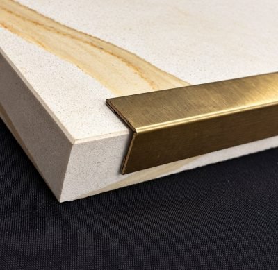 Brass-finish corner guard profile fitted to the edge of a stone slab