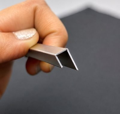 Small stainless steel J profile held between fingers, end view