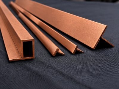 Copper L, U and box profiles with a brushed finish on a dark cloth