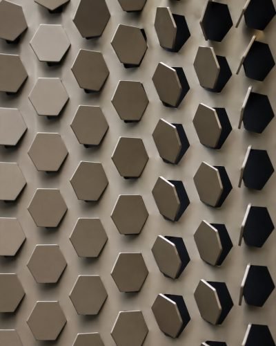 Metal coin façade panel with raised hexagons, dark bronze finish