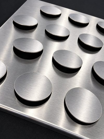 Metal coin façade panel with raised discs, brushed finish