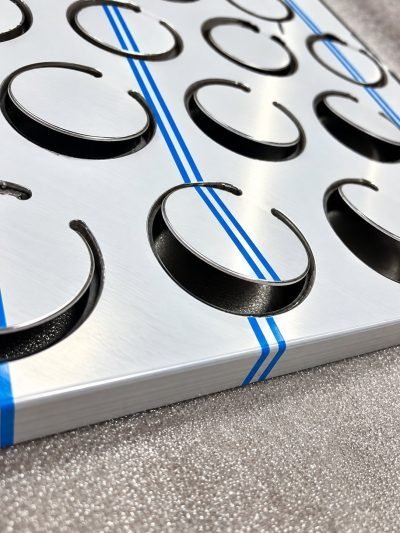 Metal coin façade panel, discs and slots, protective film on