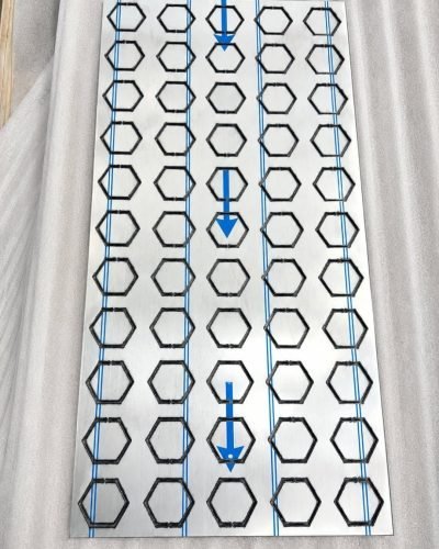 Metal coin façade panel with hexagon cut-outs, protective film on