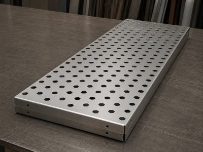 Stainless steel panel with laser-cut discs folded out of its face, in the MCS workshop