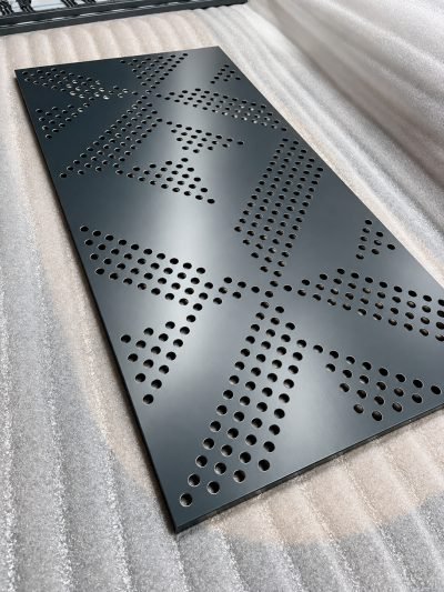 Perforated panel with a geometric dot pattern, dark grey, angled view — Perforated Façade Panels · Façade Systems