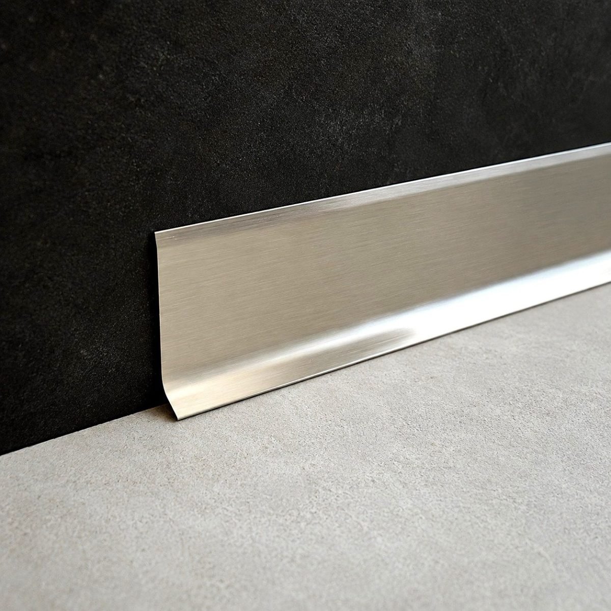 Illustration: stainless steel skirting profile at the foot of a dark wall