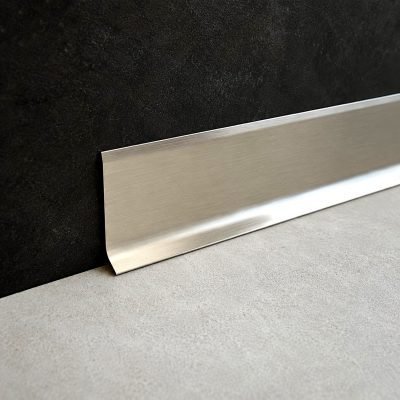 Illustration: stainless steel skirting profile at the foot of a dark wall