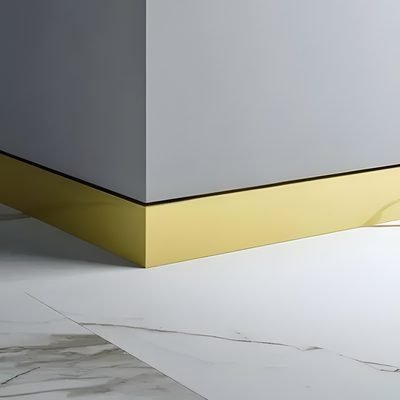 Brushed brass skirting trim at the base of a grey wall on marble