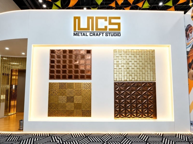 Metal panel samples in copper, gold and bronze finishes on the stand wall