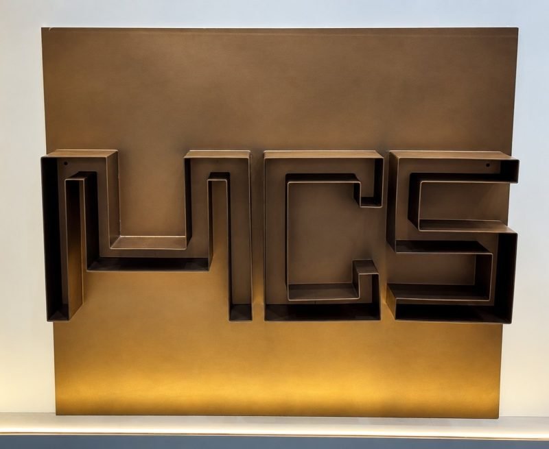 Metal Craft Studio logo in bronze on a brass-finish wall