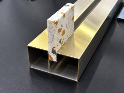 Illustration: frameless glass U channel in brass with a stone insert
