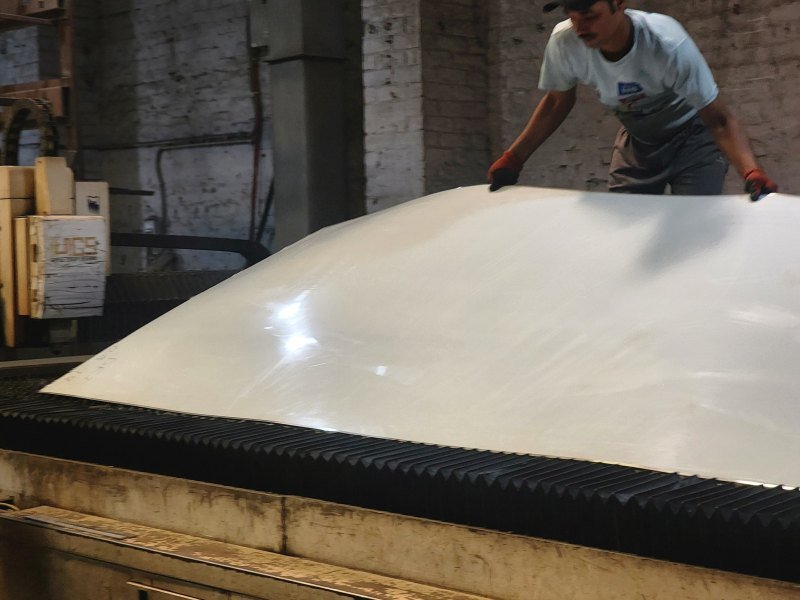 A stainless steel sheet being handled on the shop floor