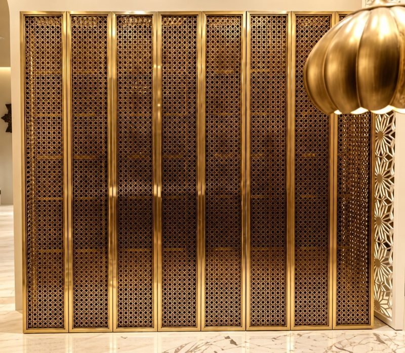 Perforated brass screen with framed panels beside a lift lobby