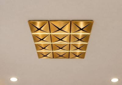 Gold metal ceiling panels with folded pyramid facets in a grid of twelve
