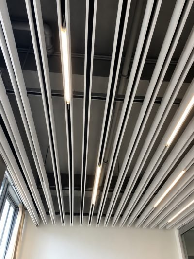 Metal baffle ceiling with linear lighting, installed