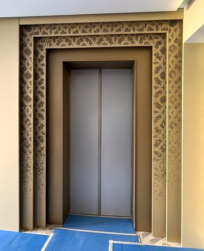 Lift portal cladding with a carved border frame in bronze finish