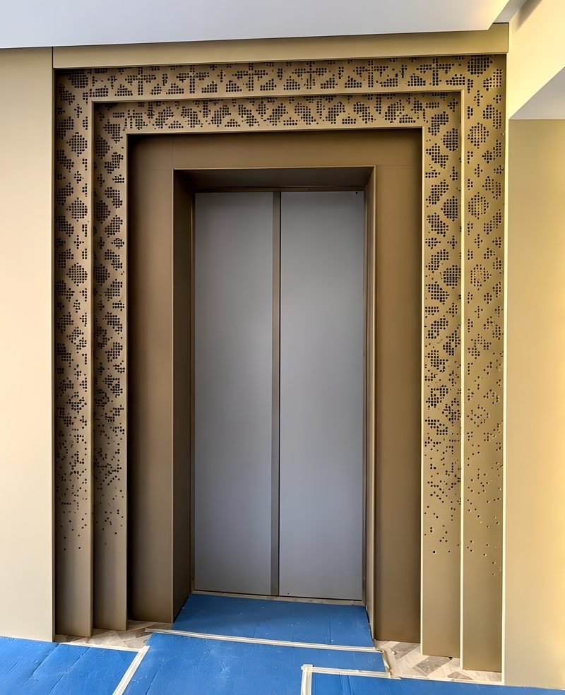 Lift portal cladding with a carved border frame in bronze finish