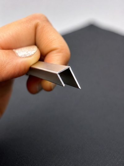 A small stainless steel U channel held between two fingers — U & C Profile · Architectural Profiles