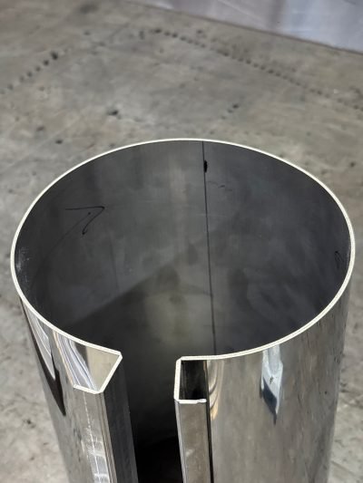 A round column cladding profile with a V-grooved return, formed from flat sheet