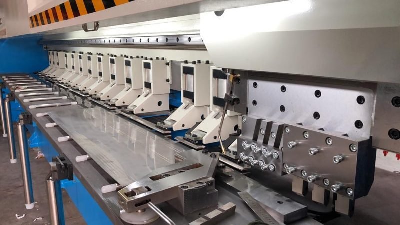 CNC V-grooving machine at Metal Craft Studio: the clamp row and a stainless steel sheet on the bed